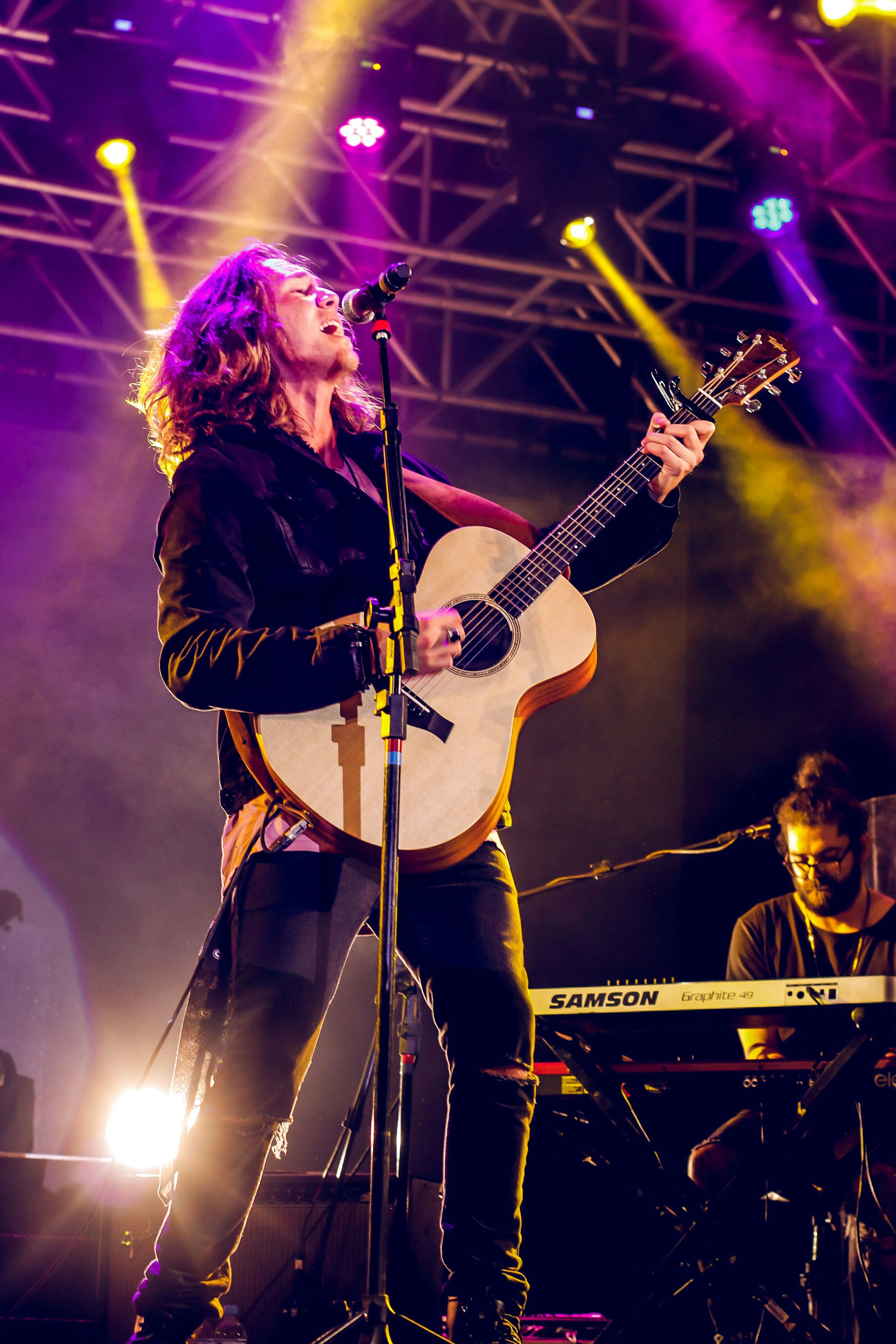 Live singer performing with an acoustic guitar under stage lights